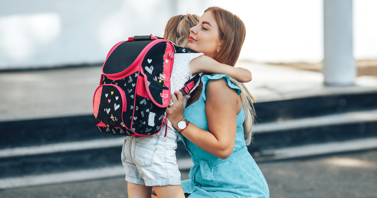 child with backpack hugging family member